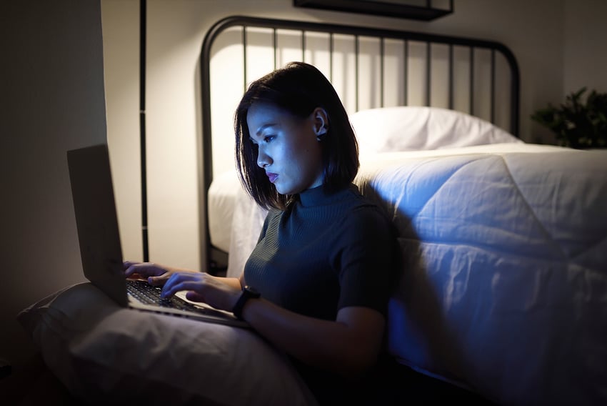 Asian woman sitting on her floor working remote on her laptop